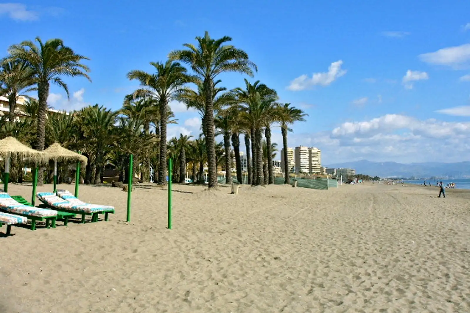 dos hamcas mirando al mar con una playa siendo la de Torremolinos y al final se ven 3 torres que son las torres de playamar y también hay un pequeña zona de palmeras al lado del mar. Prepara tú negocio en temporada alta en Torremolinos